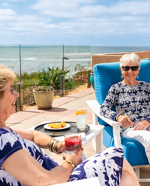 Two senior women sitting on patio overlooking the ocean at White Sands La Jolla