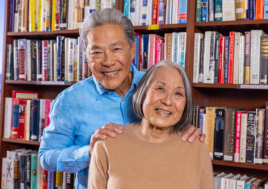Senior man with his hands on the shoulders of a senior woman in a library