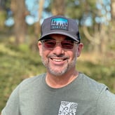 Brian Lloyd smiling outside while wearing a hat and sunglasses