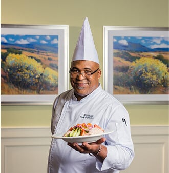 Chef of a HumanGood Life Plan Community holding up a dish