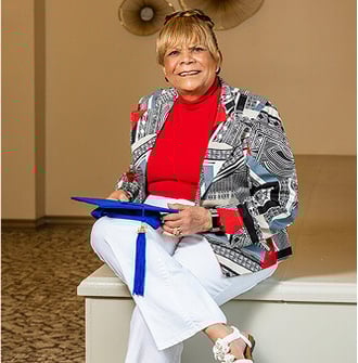 Senior woman holding a blue graduation cap