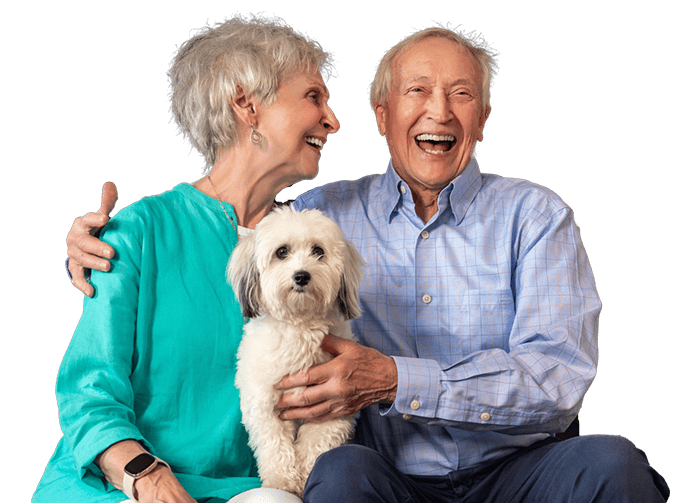 seniors smiling while holding a small dog
