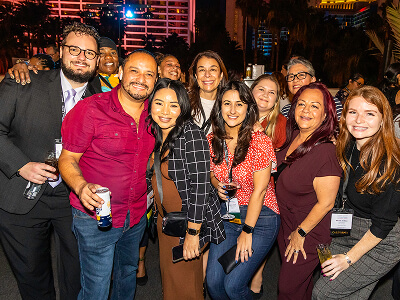 A diverse group of people smiling and posing together at a lively evening event.