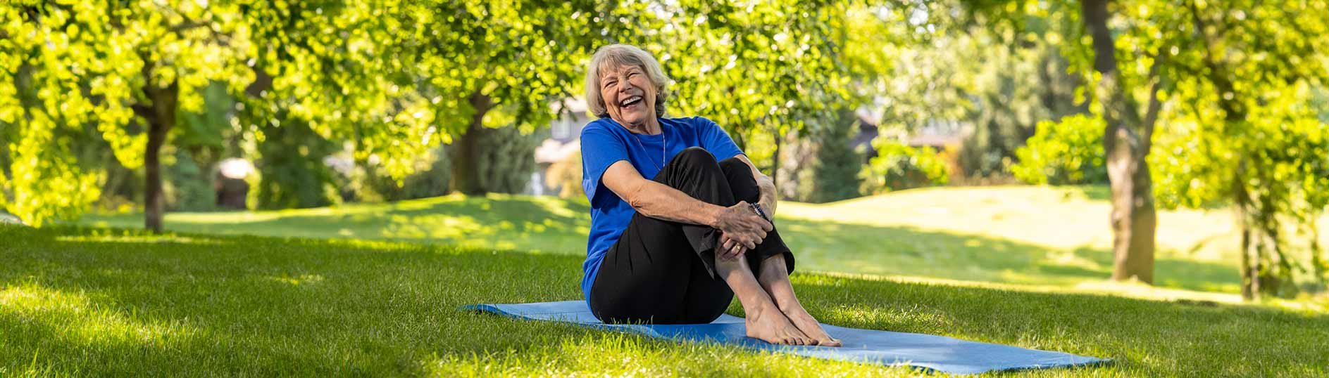 Female resident sitting on a yoga mat in the middle of a park