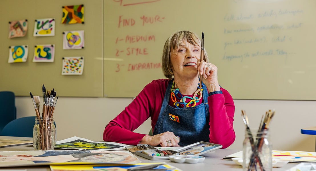 Senior woman holding a paintbrush in the community art room