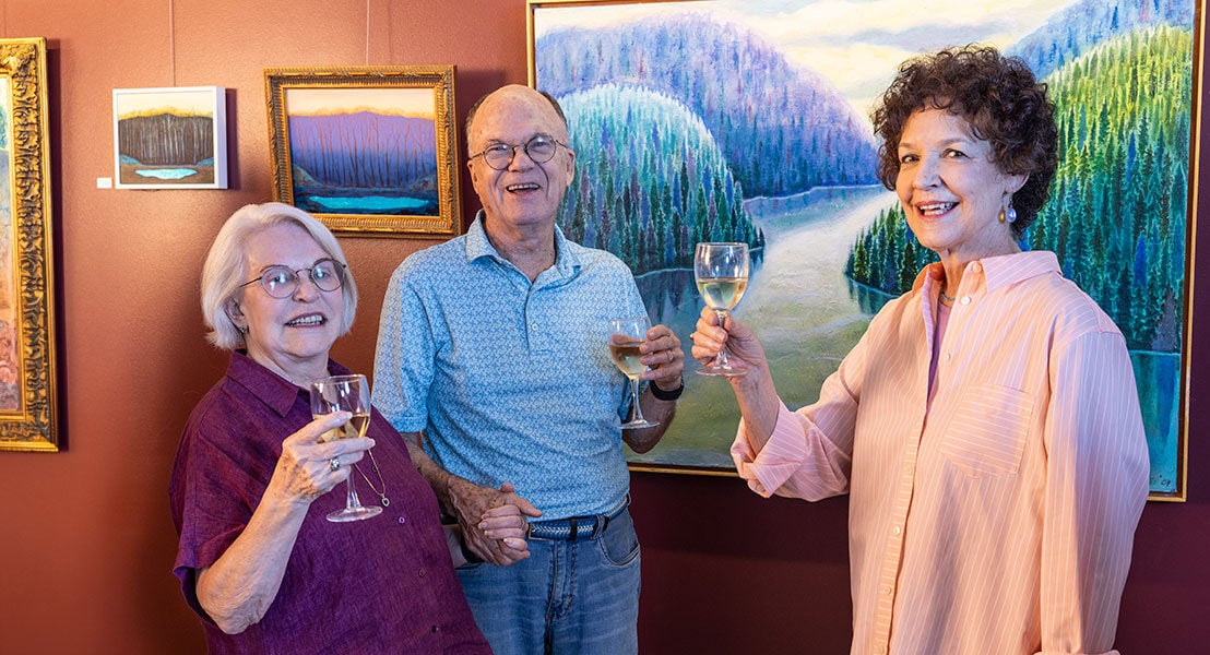 Three seniors holding wine glasses at an art exhibit
