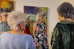 Group of seniors socializing in front of art at Plymouth Village