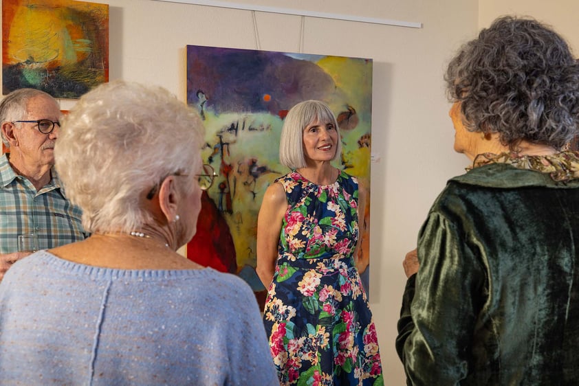 Group of seniors socializing in front of art at Plymouth Village