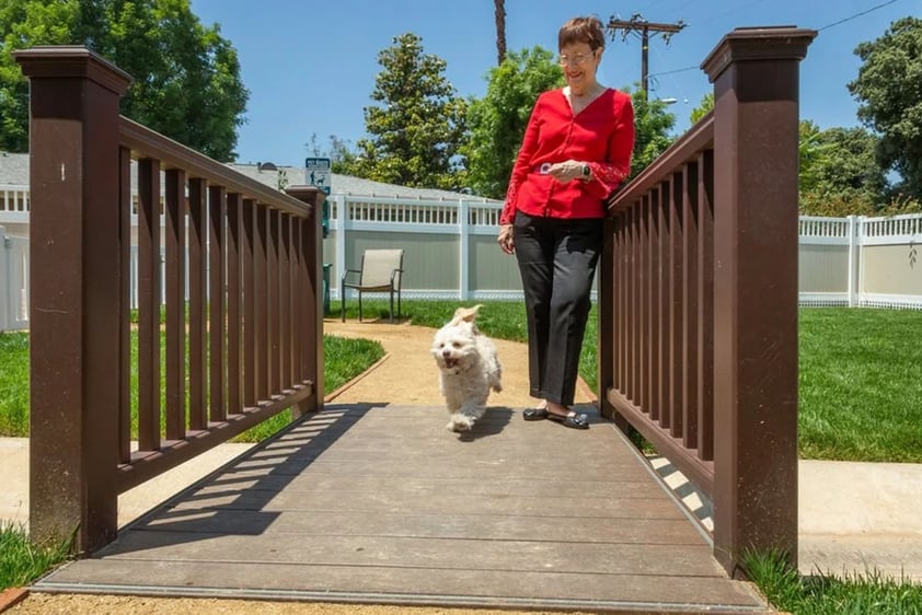 Senior women walking her small white dog to the Plymouth Village dog park