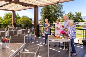 Two senior men and two senior women enjoying drinks and snacks on the Plymouth Village dining deck