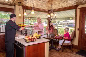 Bistro employee handing a plate of food to a senior woman