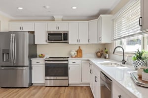Kitchen with white cabinets and countertops and stainless steel appliances in a Plymouth Village home