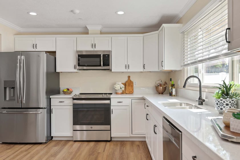 Kitchen with white cabinets and countertops and stainless steel appliances in a Plymouth Village home