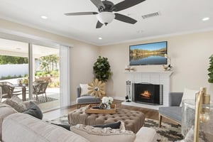 Living room with a TV hanging over a fireplace and sliding glass doors leading to a patio of a home at Plymouth Village