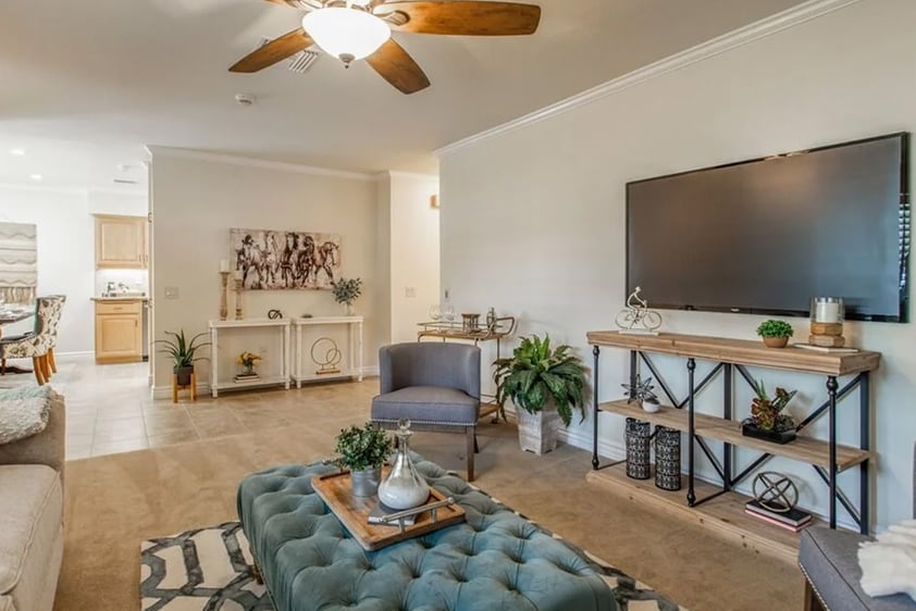 Living room with blue tufted ottoman and television in a Plymouth Village home