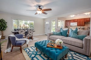 Living room with gray couch and blue tufted ottoman in a Plymouth Village home