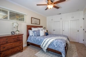 Bed with blue and white bedspread and wood furniture in a Plymouth Village home