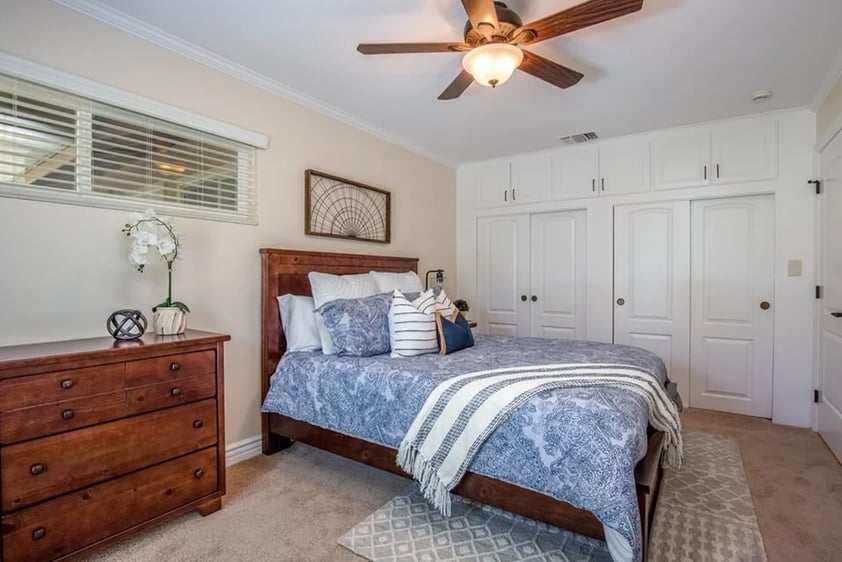 Bed with blue and white bedspread and wood furniture in a Plymouth Village home