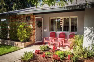 Three red Adirondack chairs outside the front door of a Plymouth Village home