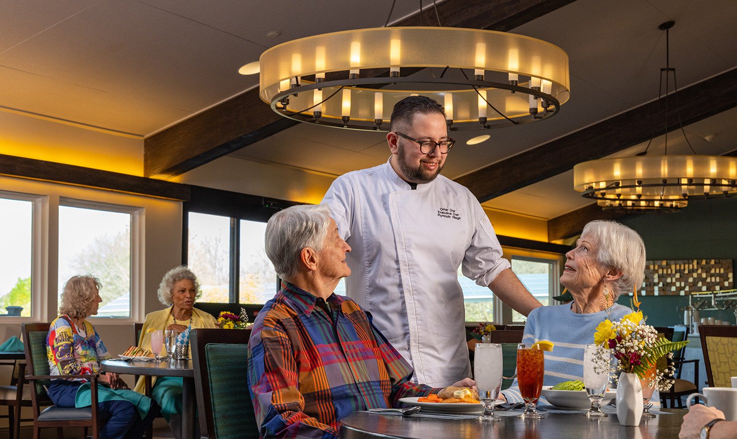 Chef visiting senior couple dining in the dining room at Plymouth Village