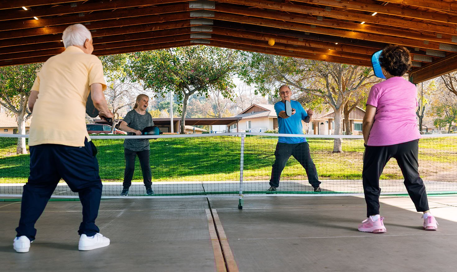 Two senior men and two senior women playing pickleball on a court at Plymouth Village