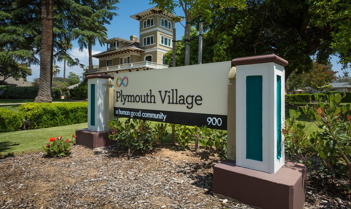 Plymouth Village sign at the entrance to the community with a large house in the background