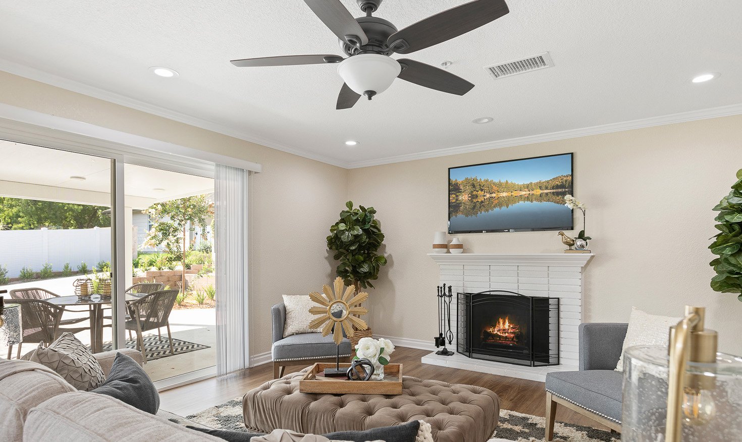 Living room with a TV hanging over a fireplace and sliding glass doors leading to a patio of a home at Plymouth Village
