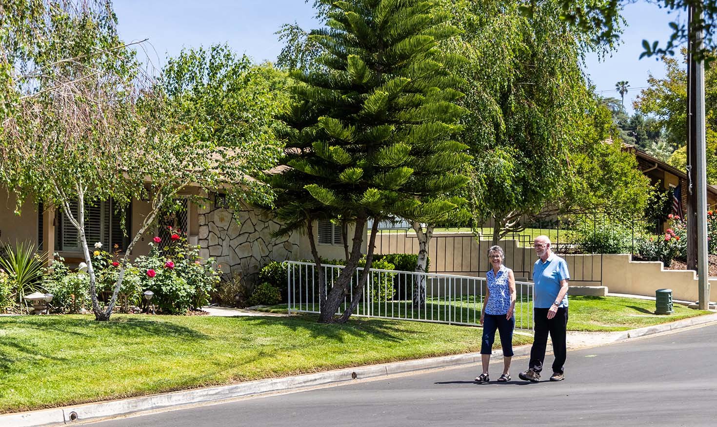 Senior man and woman walking down the road past a single-level home in Plymouth Village