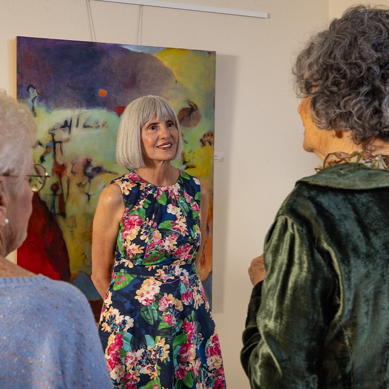Group of senior women socializing in front of art at Plymouth Village