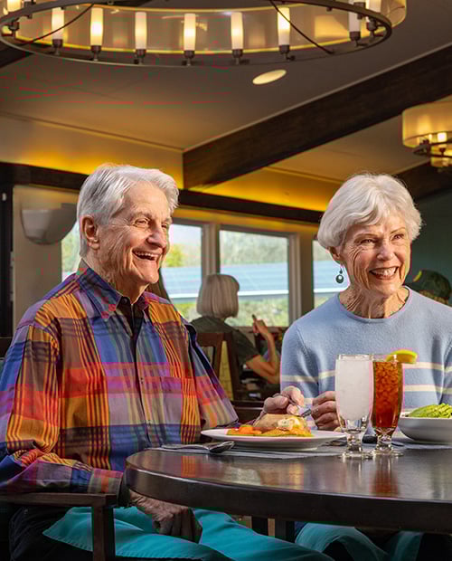 Senior man and woman eating dinner in the dining room of Plymouth Village