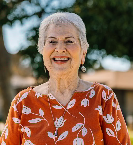 Carol smiling in orange blouse