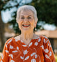Carol smiling in orange blouse