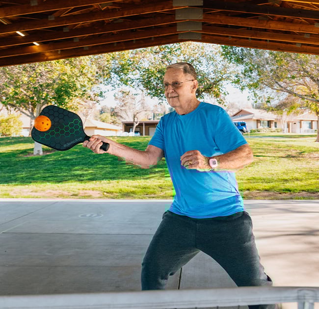 Senior man playing pickleball at Plymouth Village
