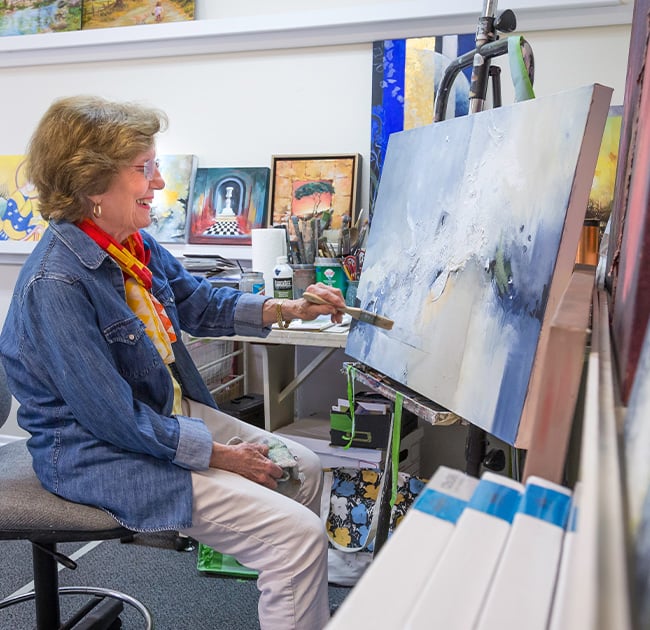 Senior woman painting in an art studio at Plymouth Village