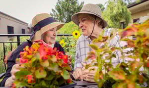 Two senior women wearing sun hats outside while gardening on the grounds of Spring Mill Pointe