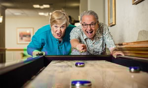 Senior man and woman playing table shuffleboard