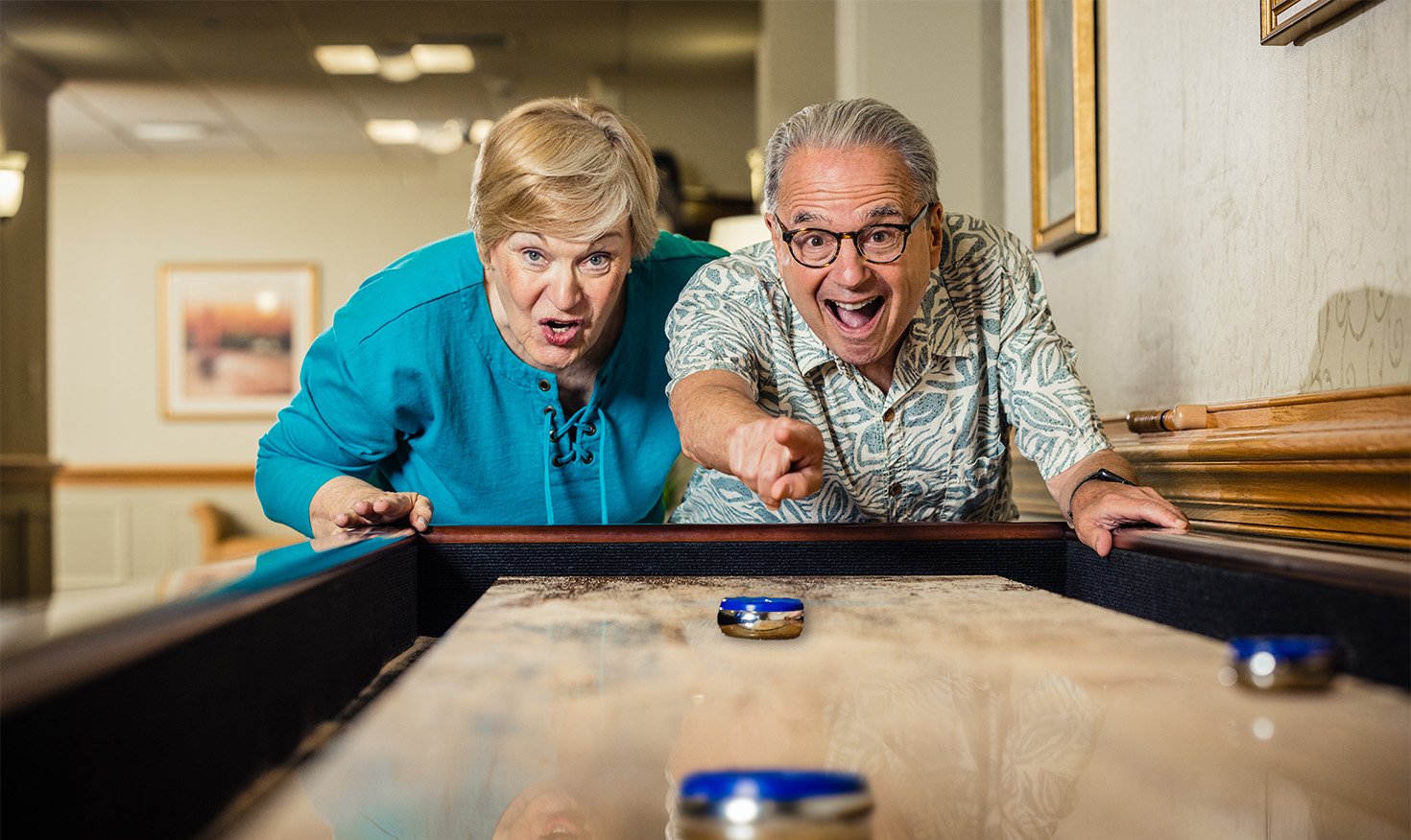 Senior man and woman playing table shuffleboard