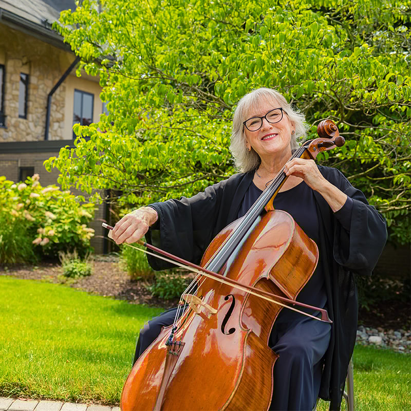 Senior woman playing the cello outside