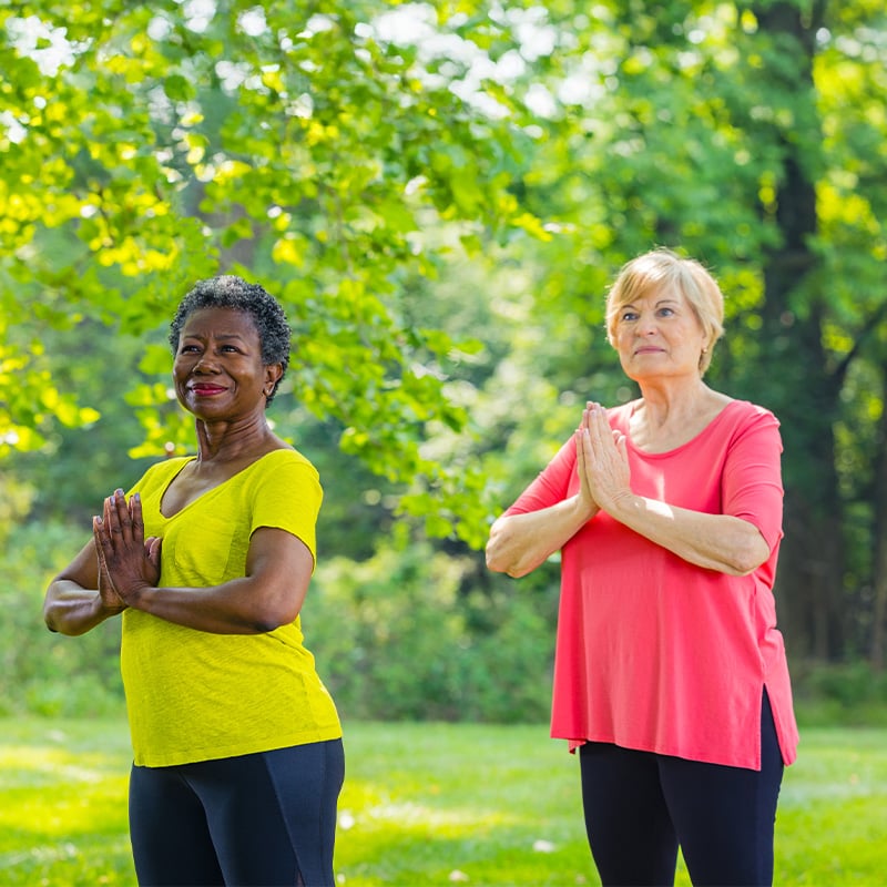 Two senior women doing yoga outdoors