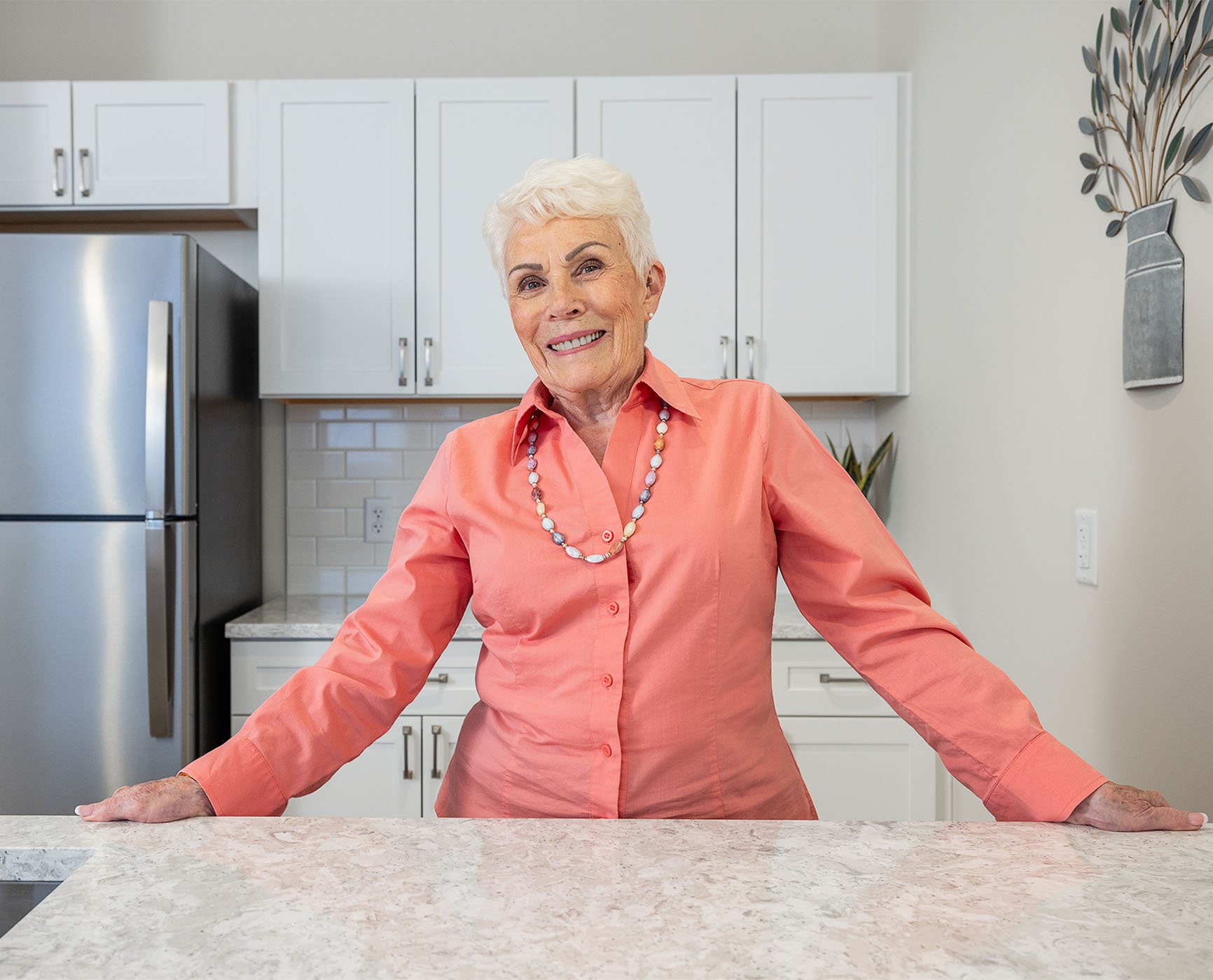 Smiling senior woman standing in the modern kitchen of her Spring Mill Pointe apartment