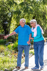 Senior couple walking on a paved path on the grounds of Westminster Gardens 