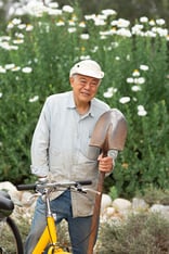 Senior man holding up a shovel in a garden at Westminster Gardens