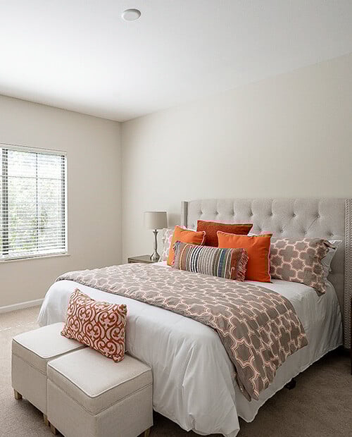 Spacious bedroom featuring a bed with a gray tufted headboard in an apartment