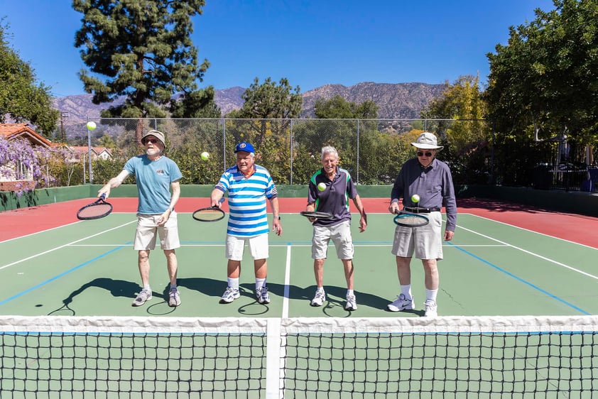 Four senior men bouncing a tennis ball