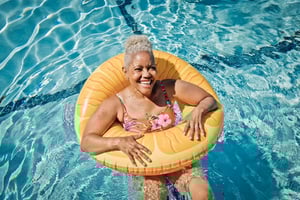 Senior woman in an orange inflatable pool tube in the Westminster Gardens pool