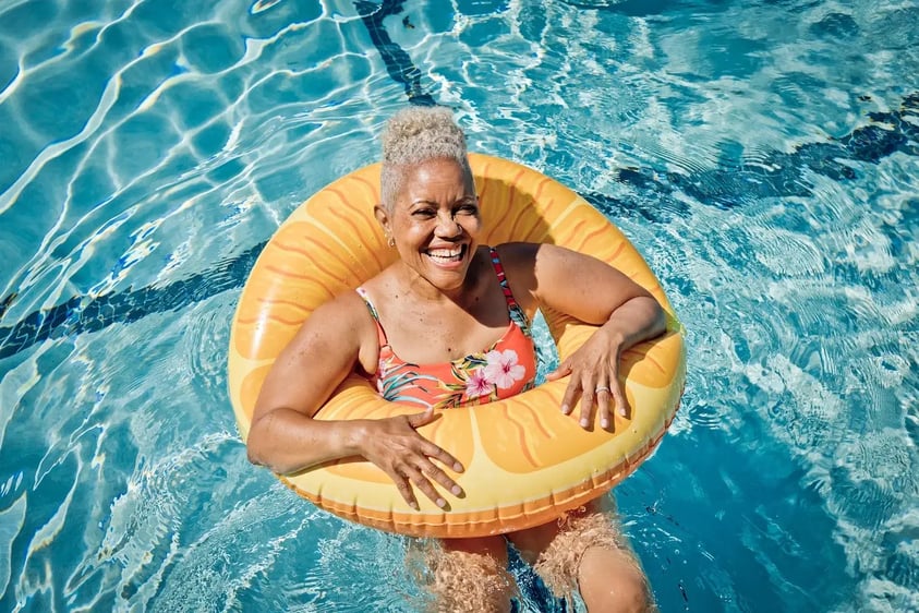 Senior woman in an orange inflatable pool tube in the Westminster Gardens pool