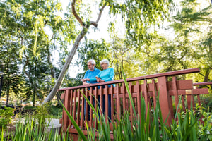 Senior couple standing on a bridge on the grounds of Westminster Gardens
