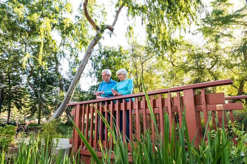 Senior couple standing on a bridge on the grounds of Westminster Gardens