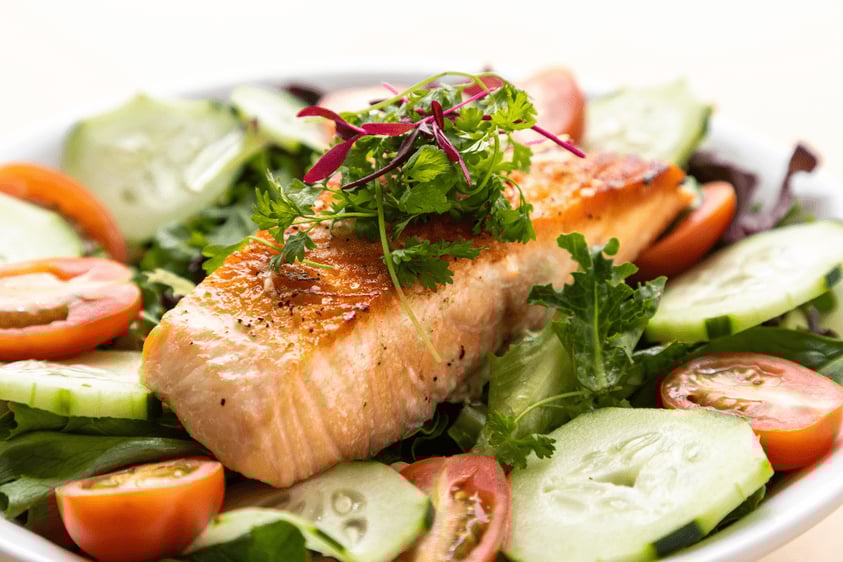Close-up of a plate of salmon on a bed of vegetables