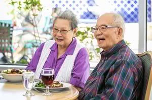 Senior couple with food and wine in the dining room at Westminster Gardens